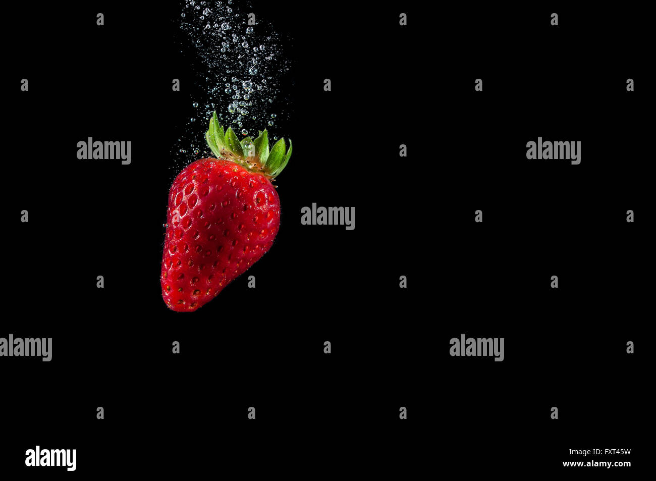 Spruzzi di fragole in acqua immergersi Foto Stock
