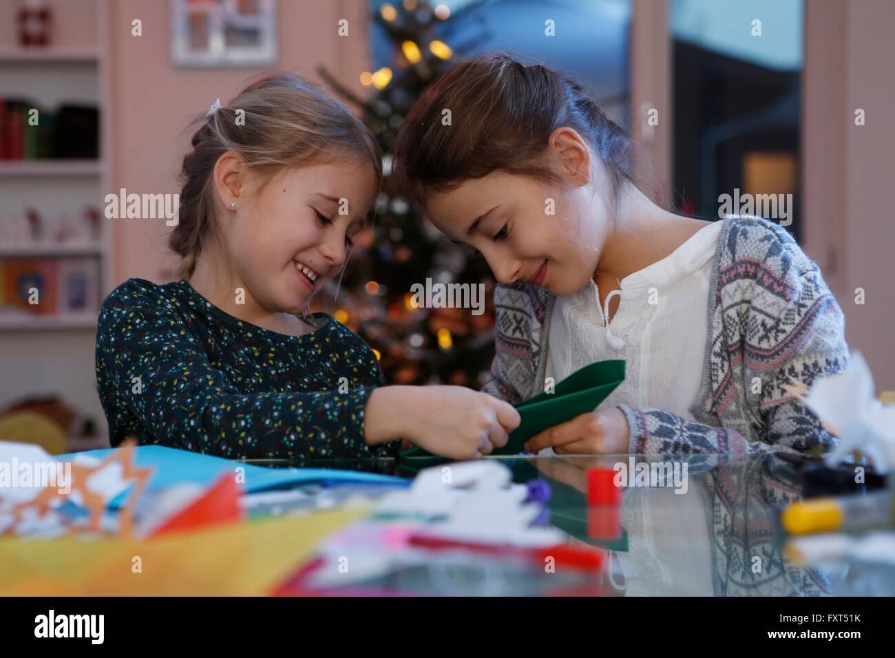 Le ragazze a tavola facendo il Natale carta artigianale sorridente Foto Stock