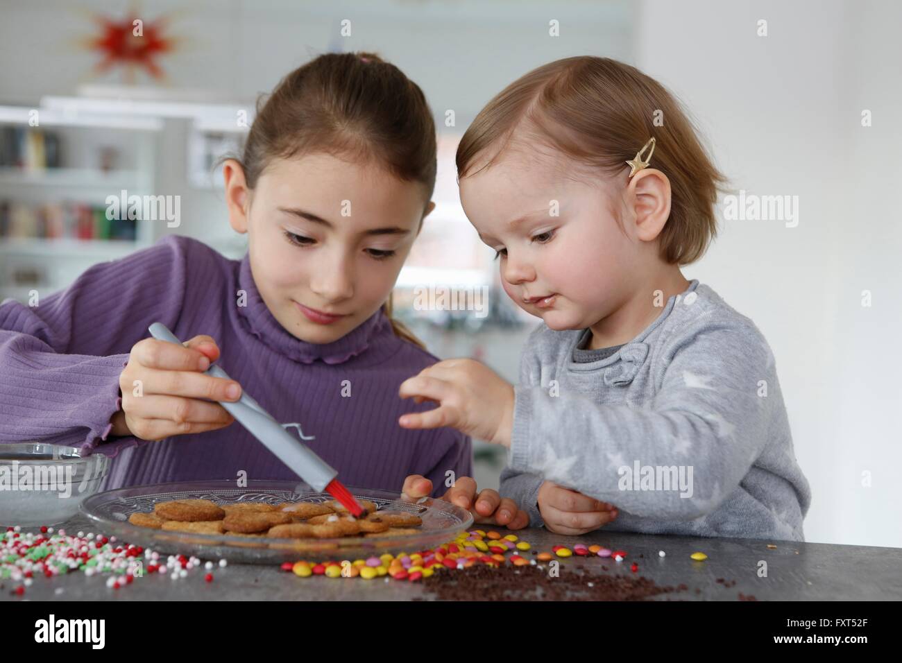 Le ragazze al bancone cucina decorare i cookie Foto Stock