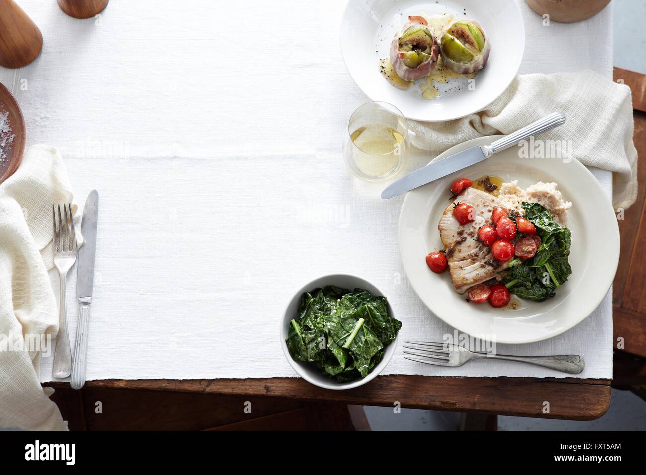 Vista aerea del pasto tabella con piatto di prosciutto avvolto figg, appassì spinaci, pomodori ciliegini, bistecca di tonno e capperi Foto Stock