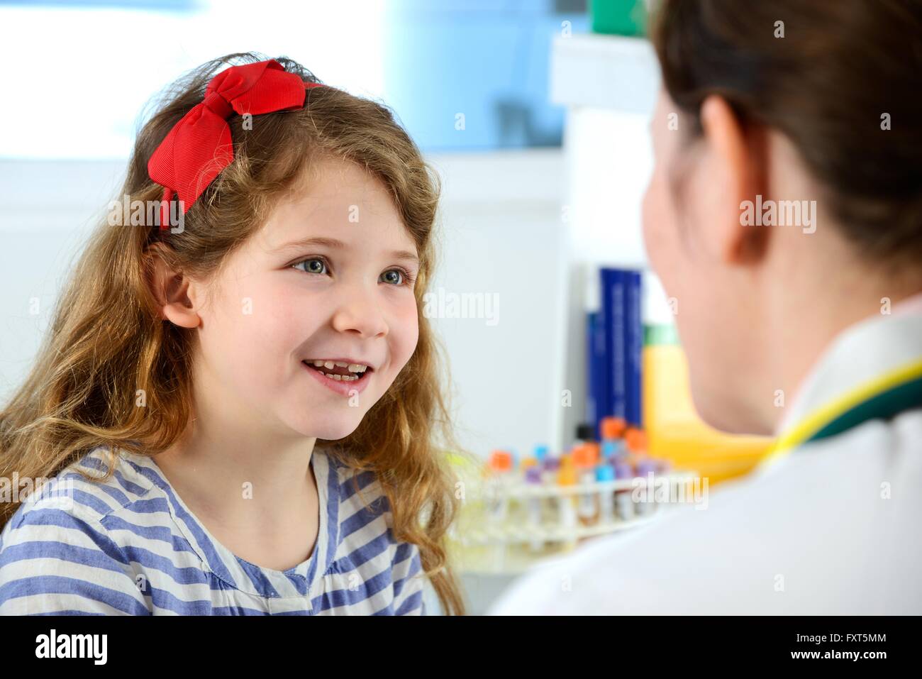 Vista sulla spalla della ragazza con consulenza medico in clinica, sorridente Foto Stock