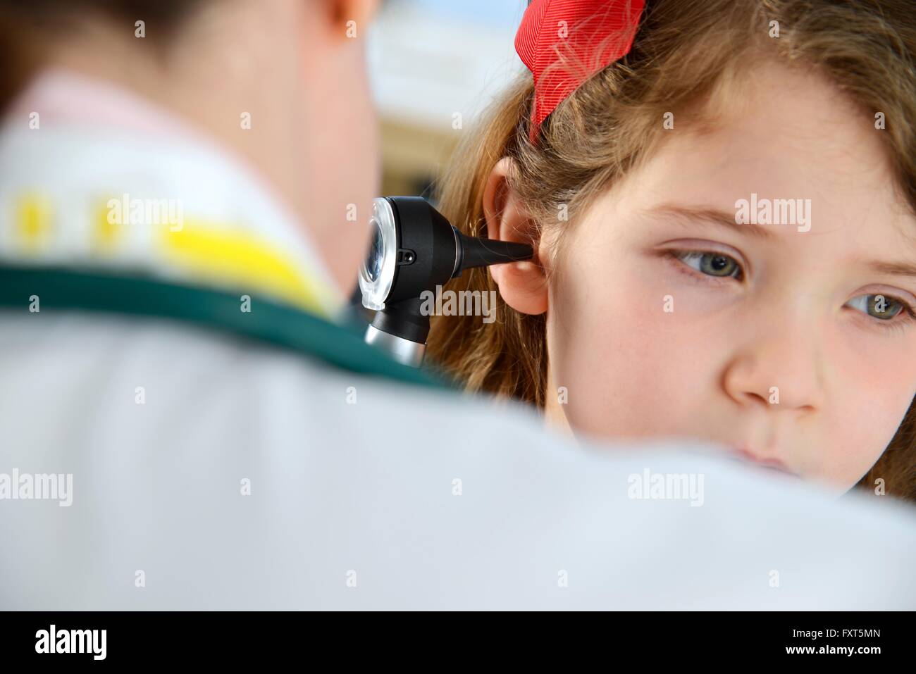 Vista sulla spalla del medico conducendo otoscopy esame sulla ragazza Foto Stock