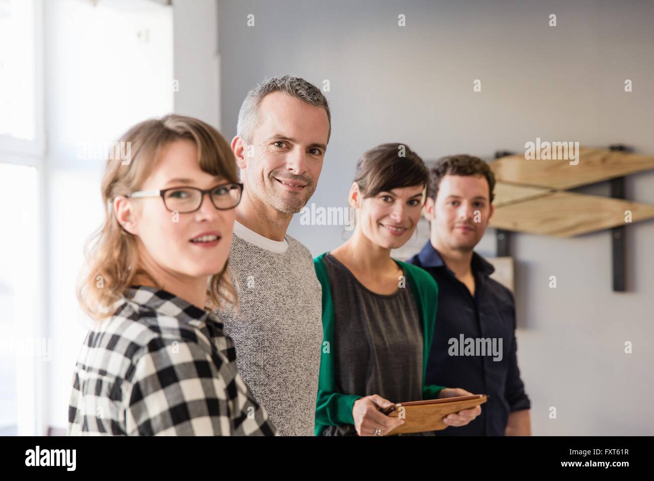 I colleghi a fianco a fianco in azienda ufficio digitale compressa guardando sorridente della fotocamera Foto Stock