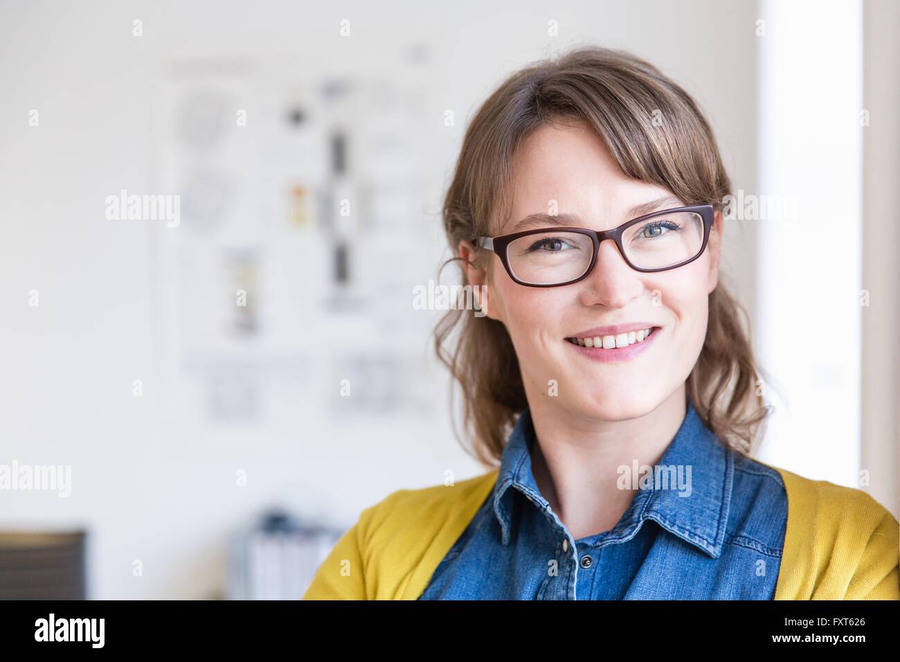 Ritratto di giovane donna che indossa occhiali guardando sorridente della fotocamera Foto Stock