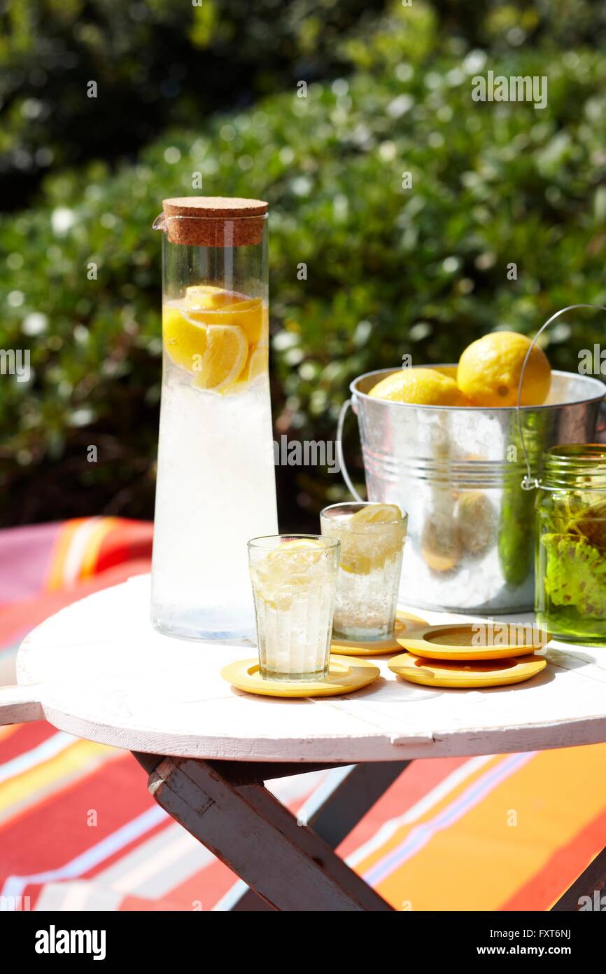 Il Limoncello soda in caraffa di vetro e il secchiello del ghiaccio di limoni sul tavolo Foto Stock