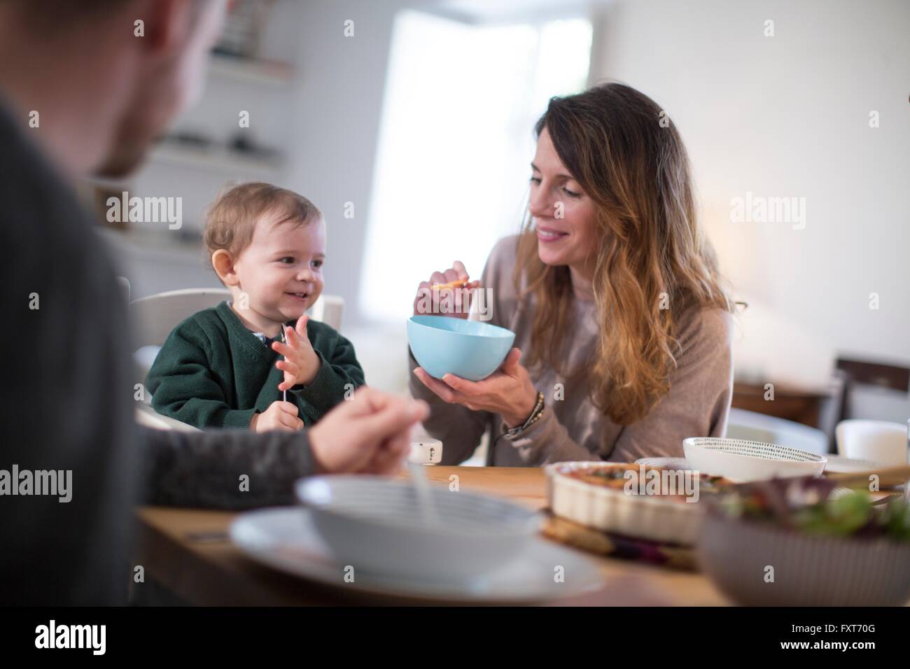 I genitori al tavolo da pranzo alimentare sorridente baby boy Foto Stock