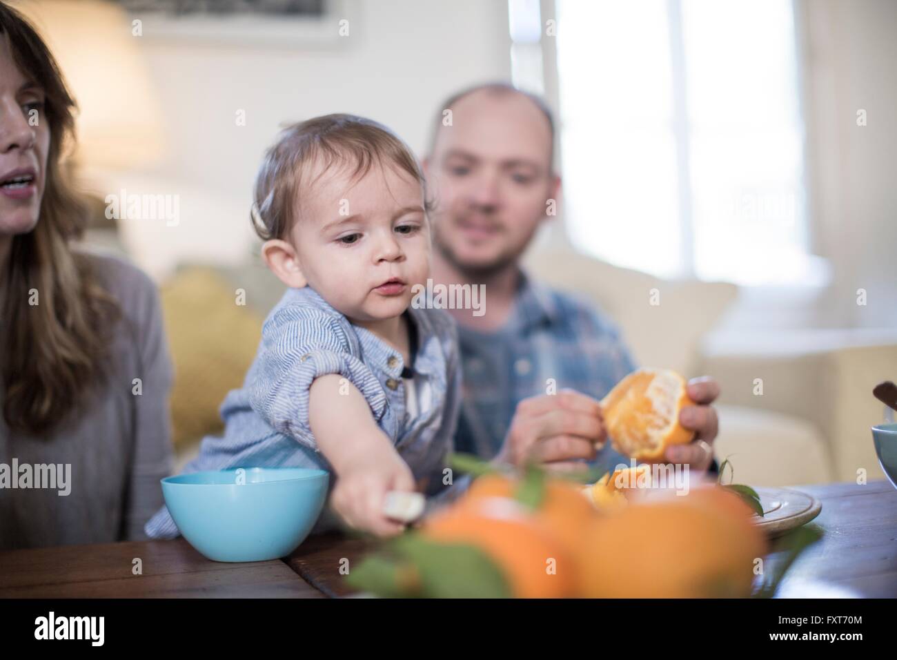 I genitori a pranzo con baby boy, peeling arancione Foto Stock