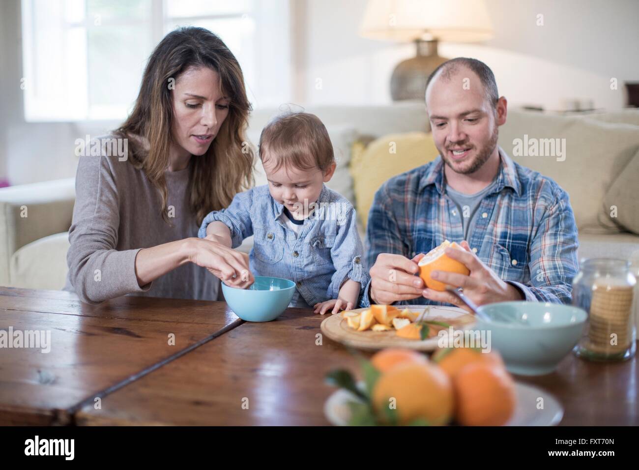 I genitori a pranzo con baby boy, peeling arancione Foto Stock