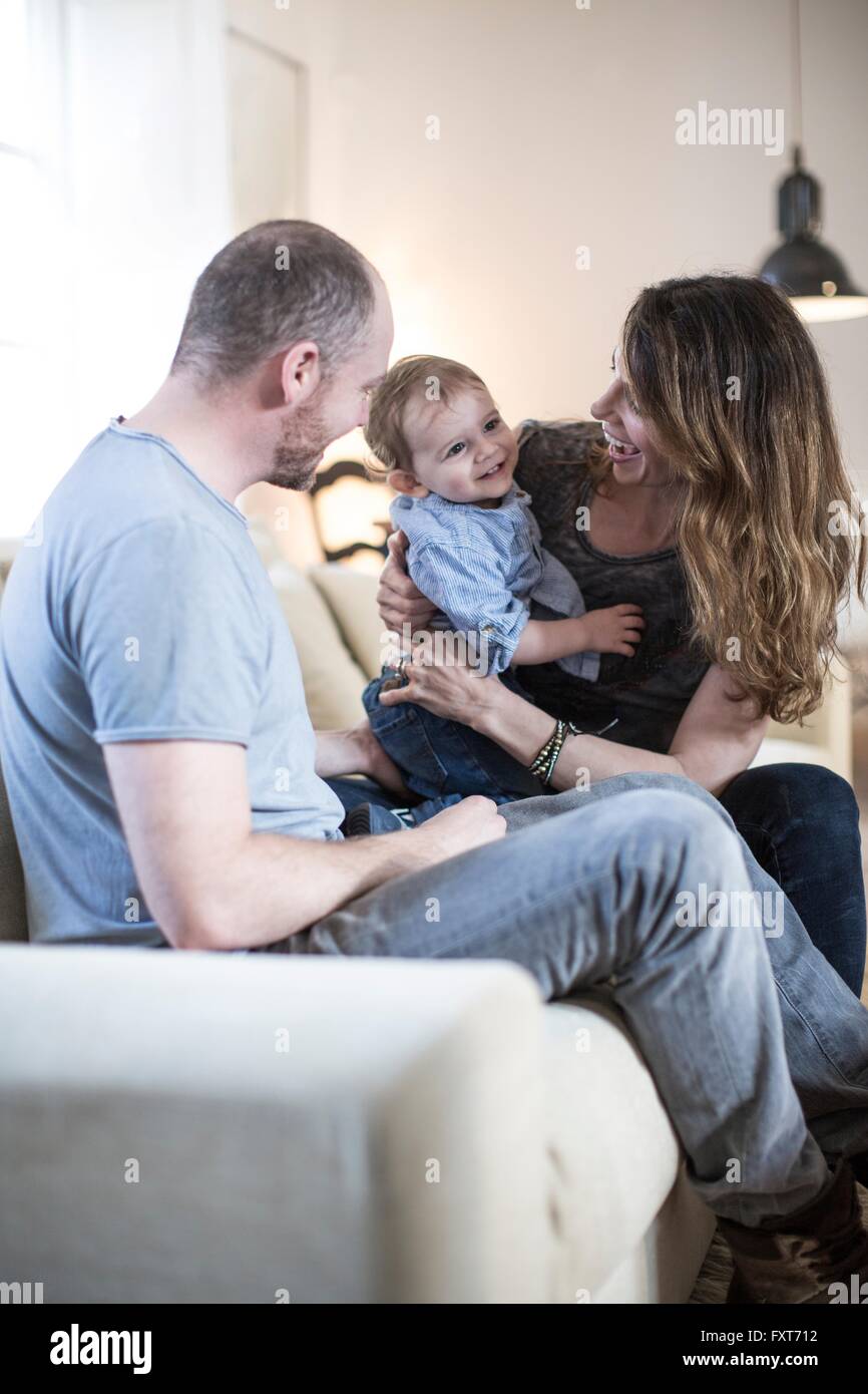 I genitori seduti sul divano a giocare con sorridente baby boy Foto Stock