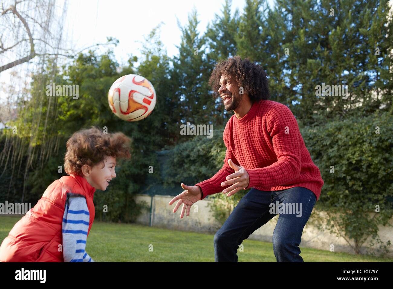 Padre e figlio giocando con il calcio nel giardino sorridente Foto Stock