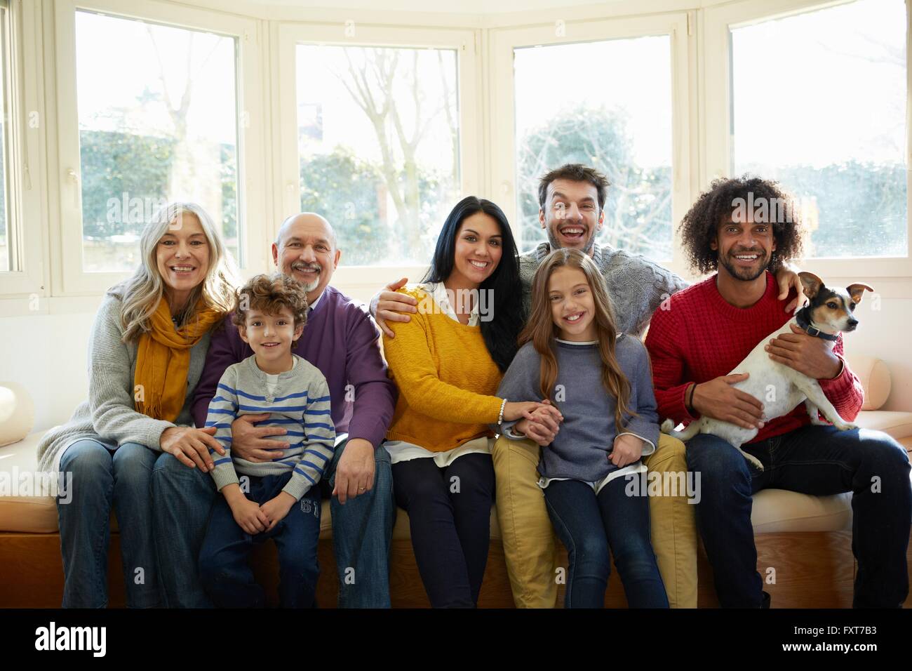 Generazione di più la famiglia e cane sul sedile della finestra guardando sorridente della fotocamera Foto Stock