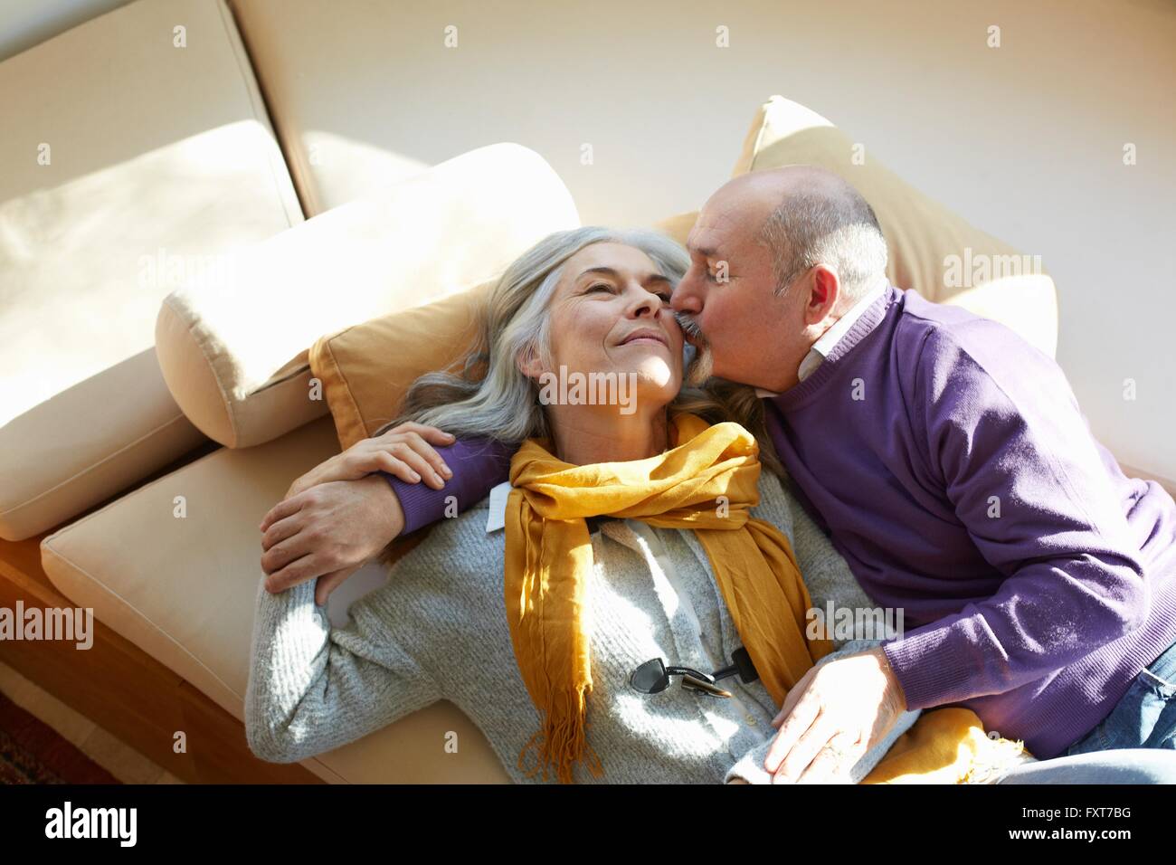 Angolo di Alta Vista della coppia matura giacente sulla finestra sedile, un bacio sulla guancia Foto Stock
