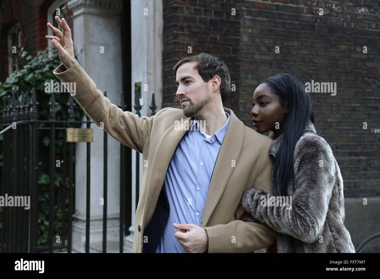 Giovane all'aperto, a braccetto, uomo salutando taxi Foto Stock