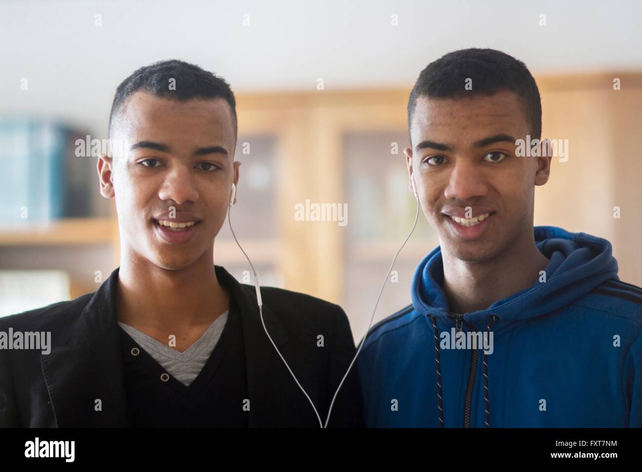 Ritratto di due fratelli gemelli, condivisione di auricolari Foto Stock