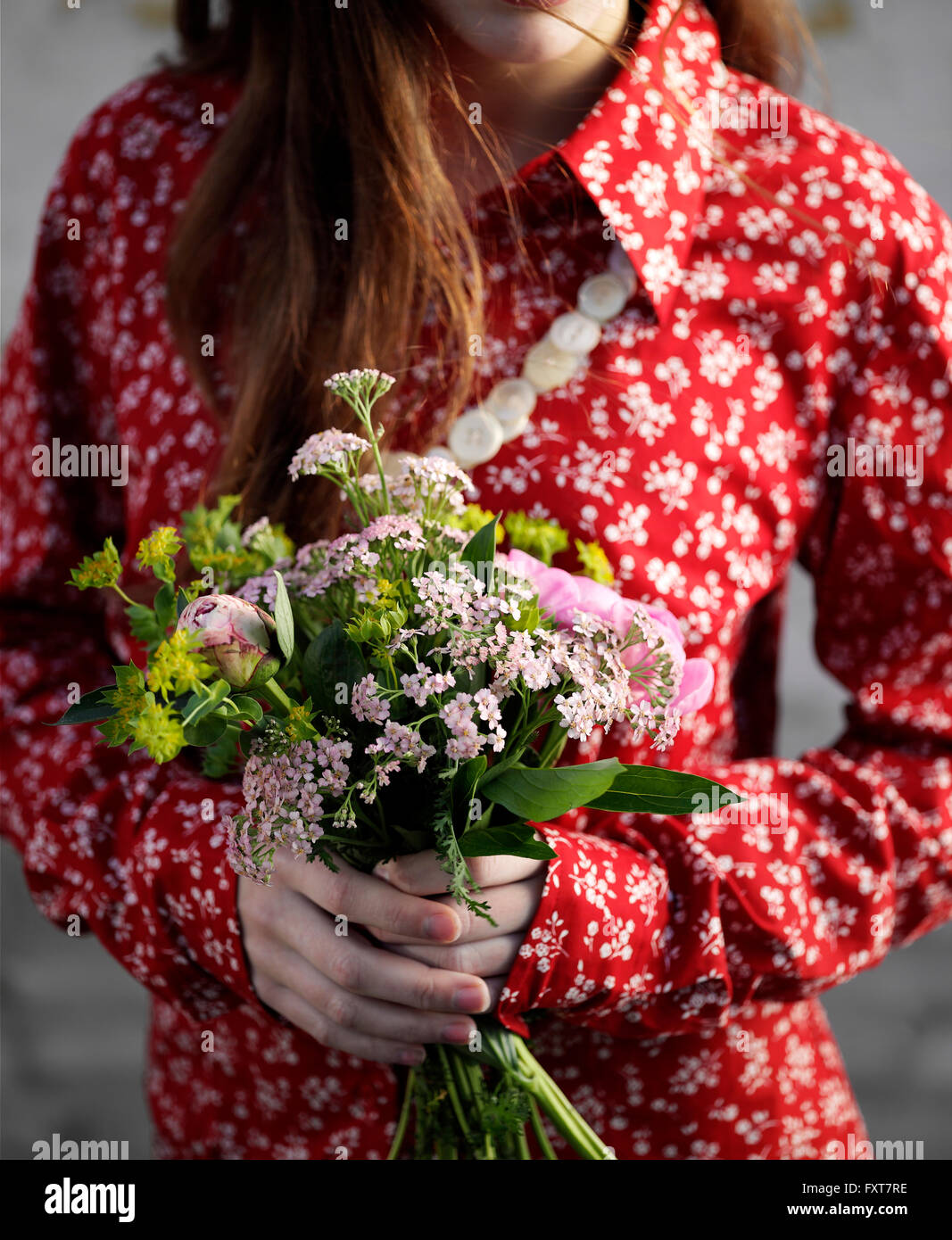 Ritagliato shot della donna che indossa rosso camicetta floreale holding mazzo di fiori Foto Stock