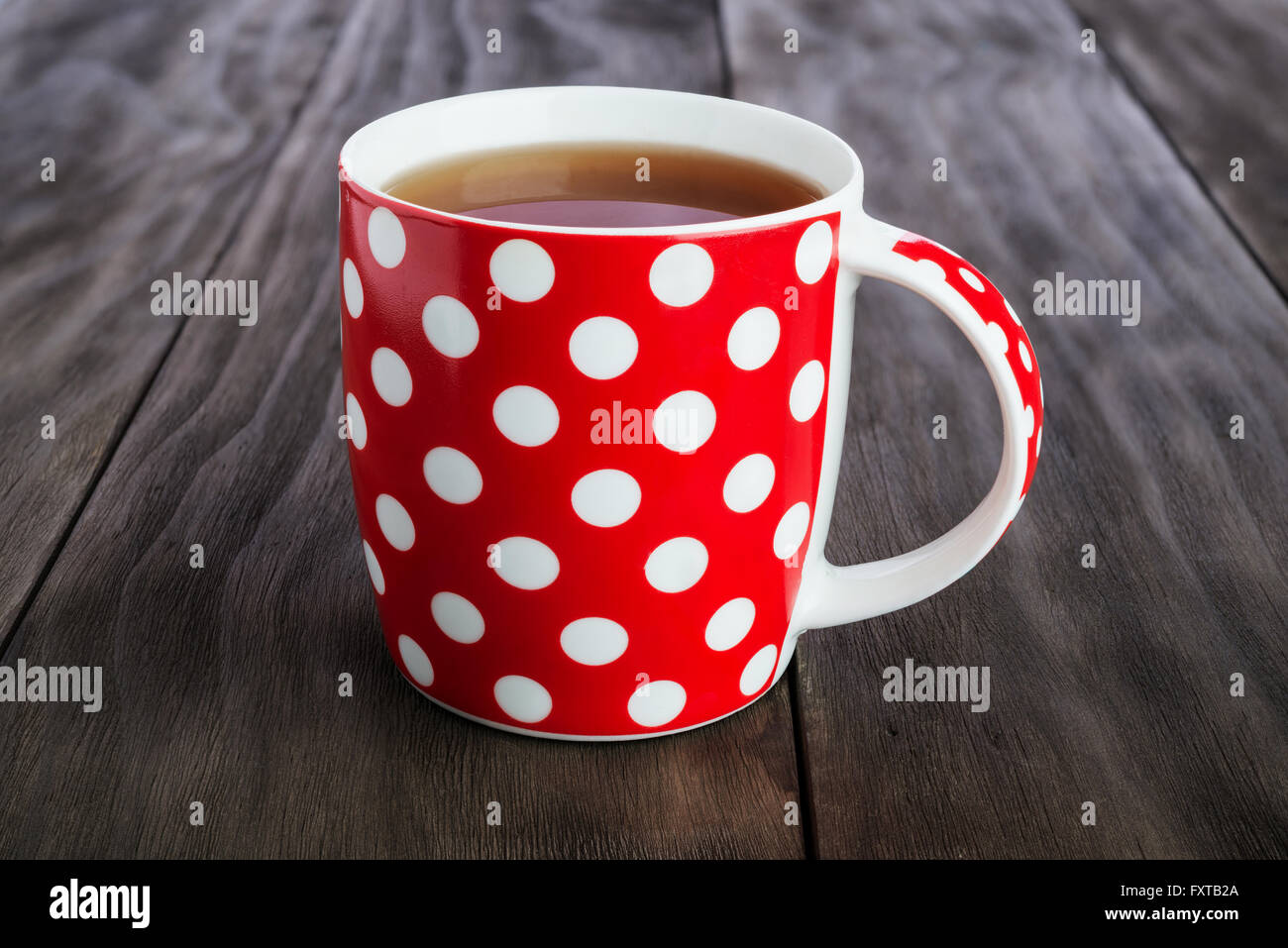 La Polka Dots red tazza di tè su vintage sfondo di legno Foto Stock