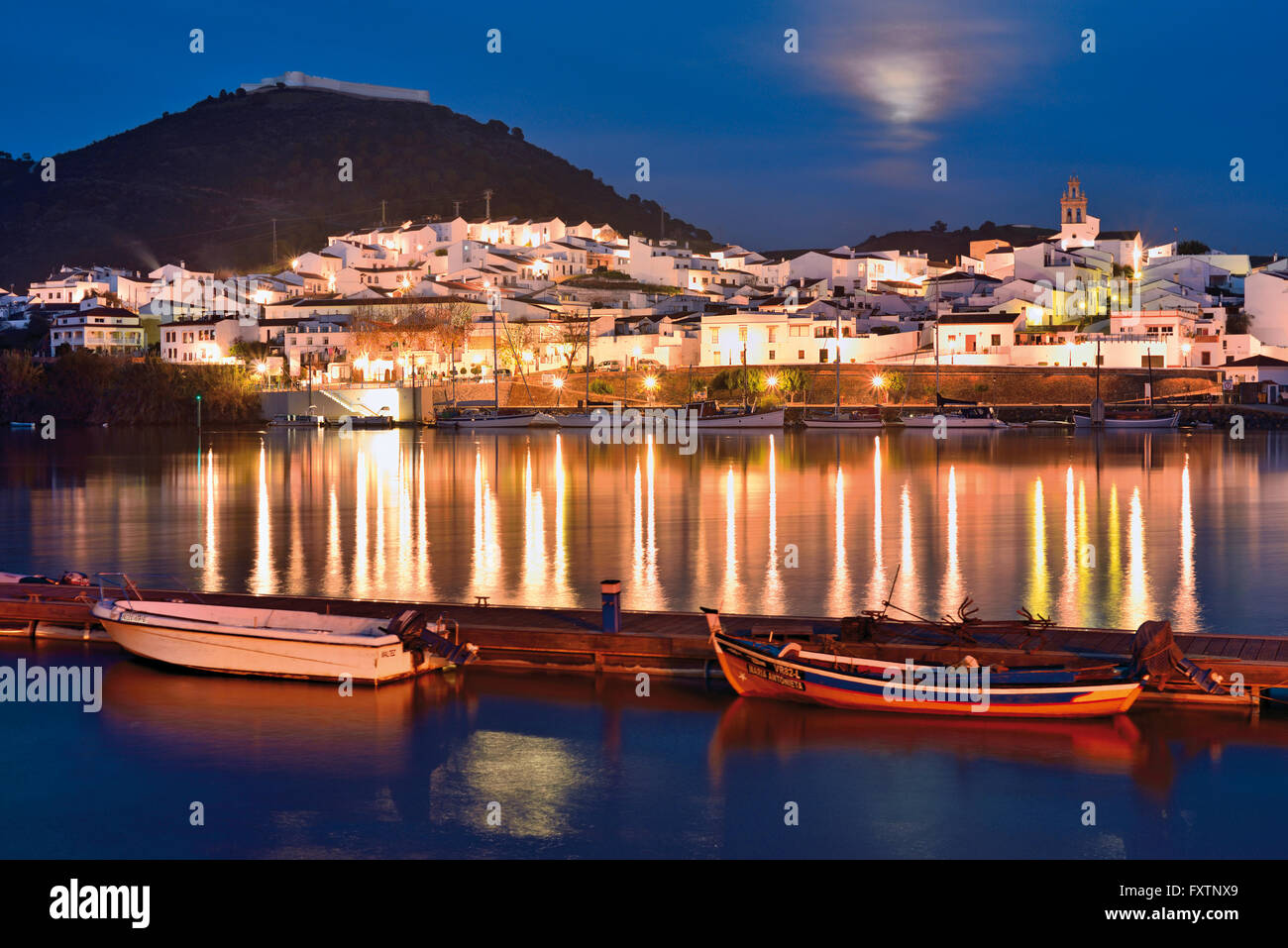 Il Portogallo, Algarve: vista notturna di spagnolo riverside village San Lucar del Guadiana visto dal porto di Alcoutim Foto Stock