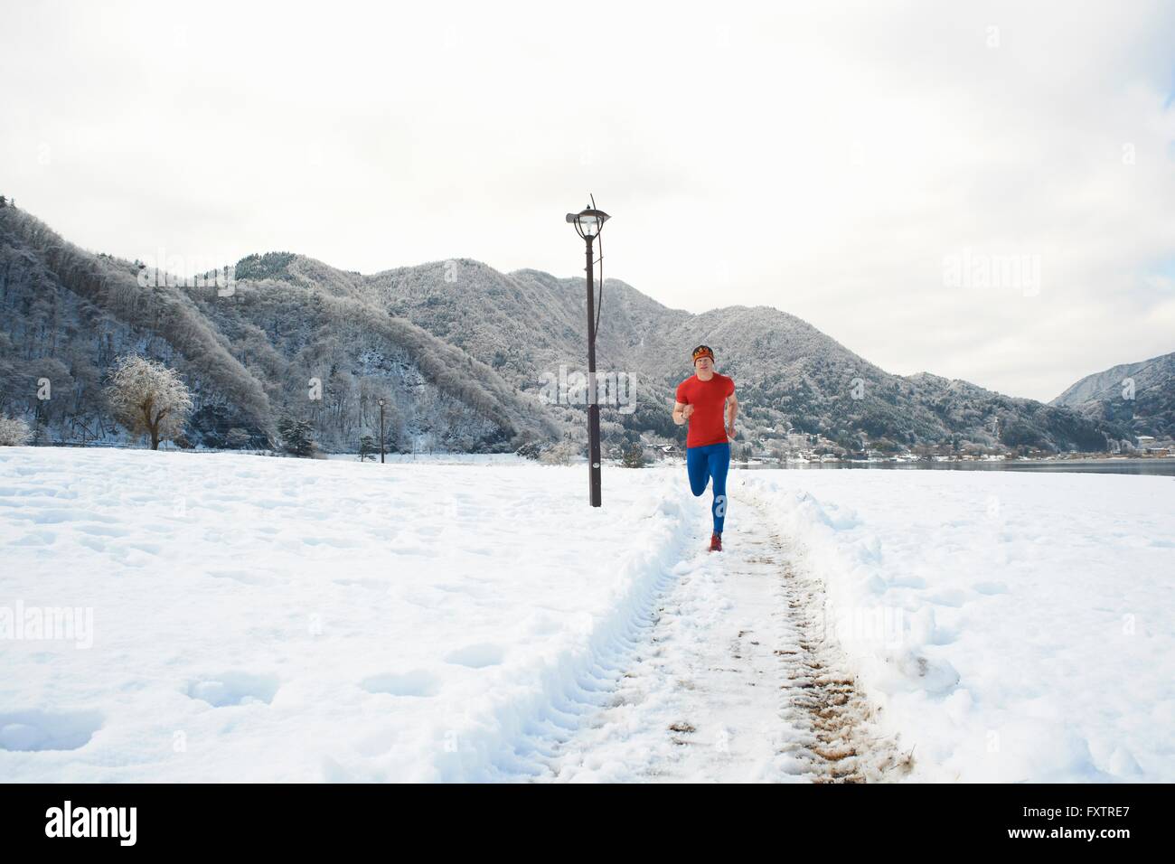 Runner maschio lungo la coperta di neve le vie, Lago Kawaguchiko, il Monte Fuji, Giappone Foto Stock