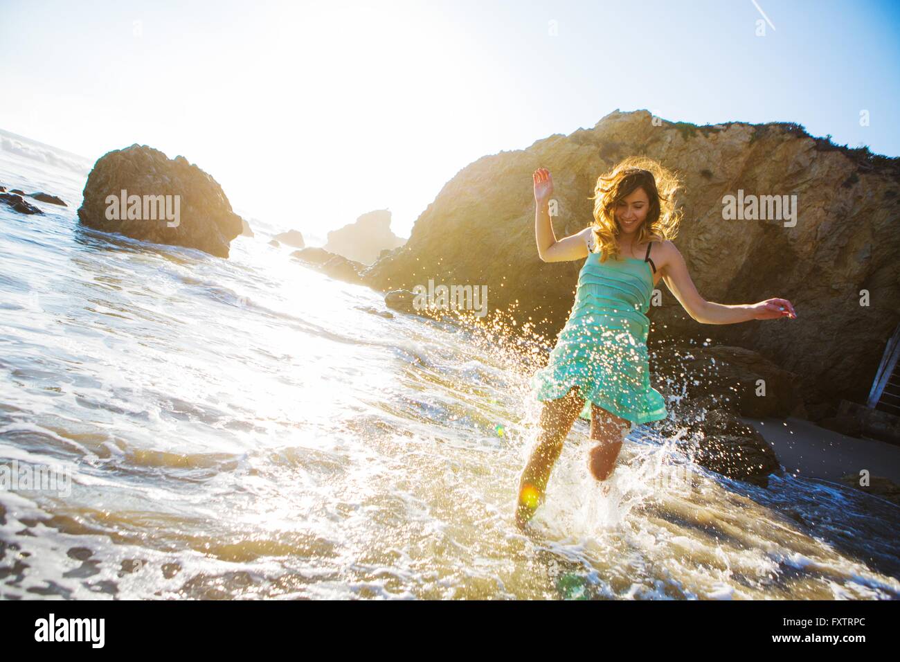 Giovane donna schizzi in acqua sulla spiaggia Foto Stock