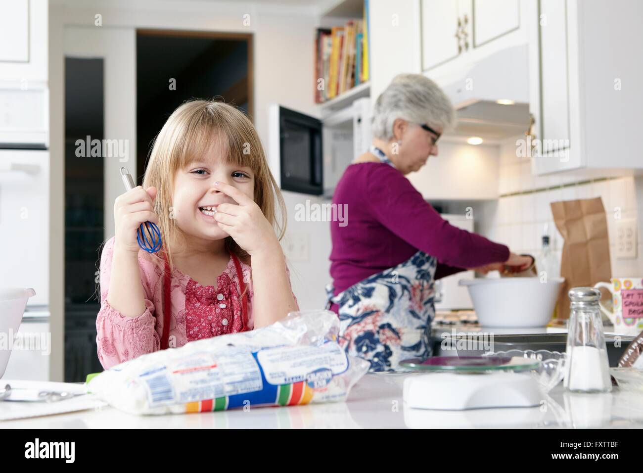 Ritratto di ragazza con una frusta mentre la cottura con la nonna Foto Stock