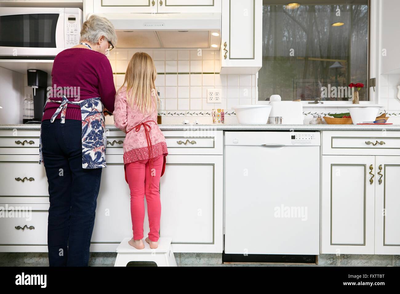 Vista posteriore di una ragazza e la nonna permanente al piano di cottura per cucina Foto Stock
