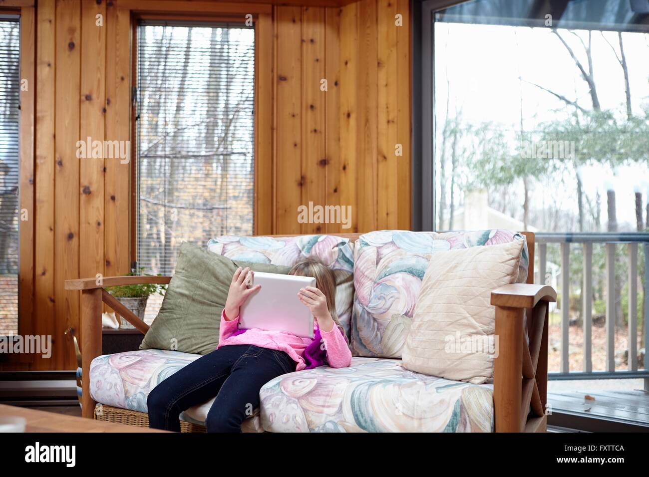 Ragazza slouching sul divano con tavoletta digitale Foto Stock