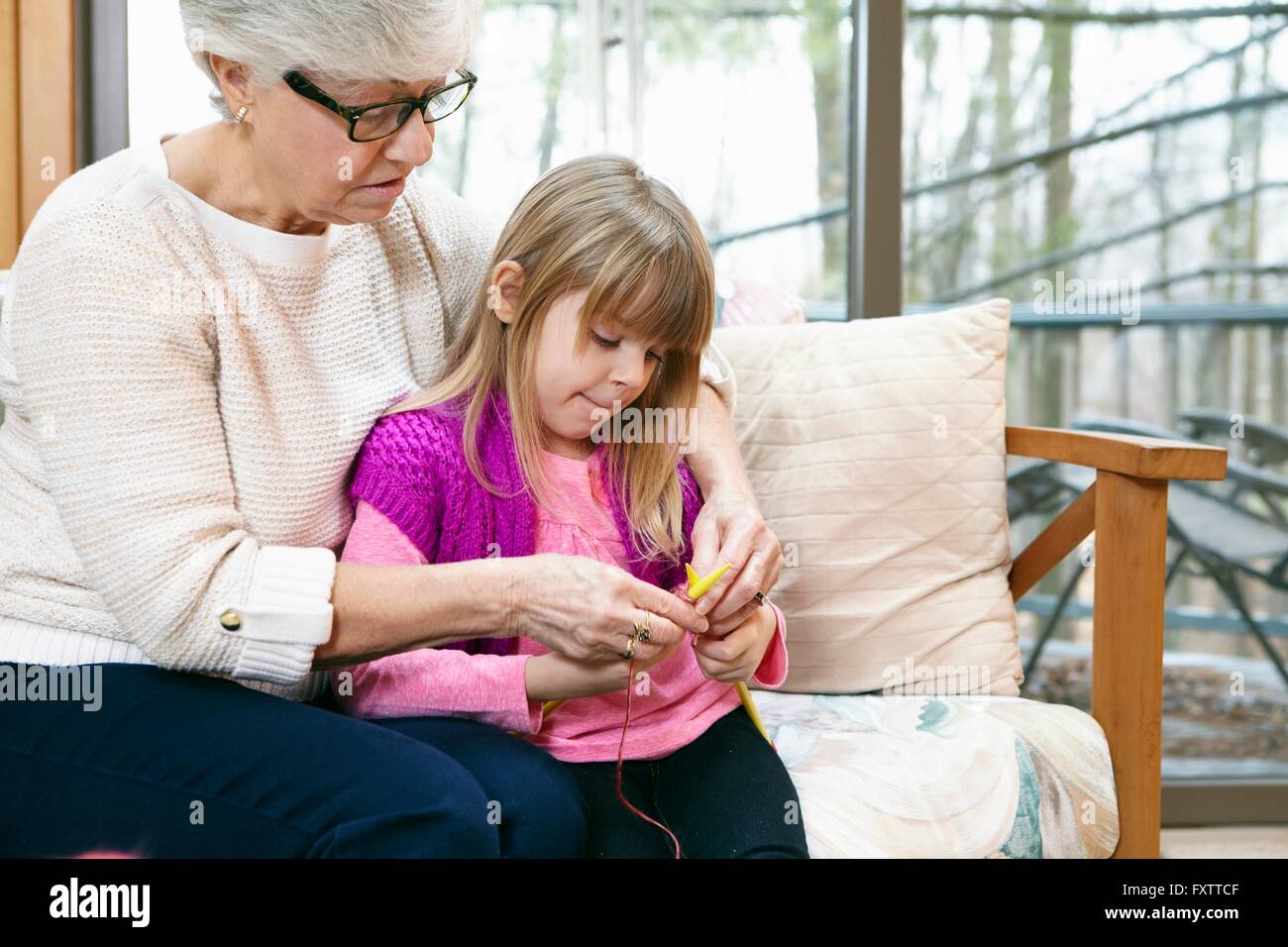 Donna Senior e nipote tessitura sul divano Foto Stock