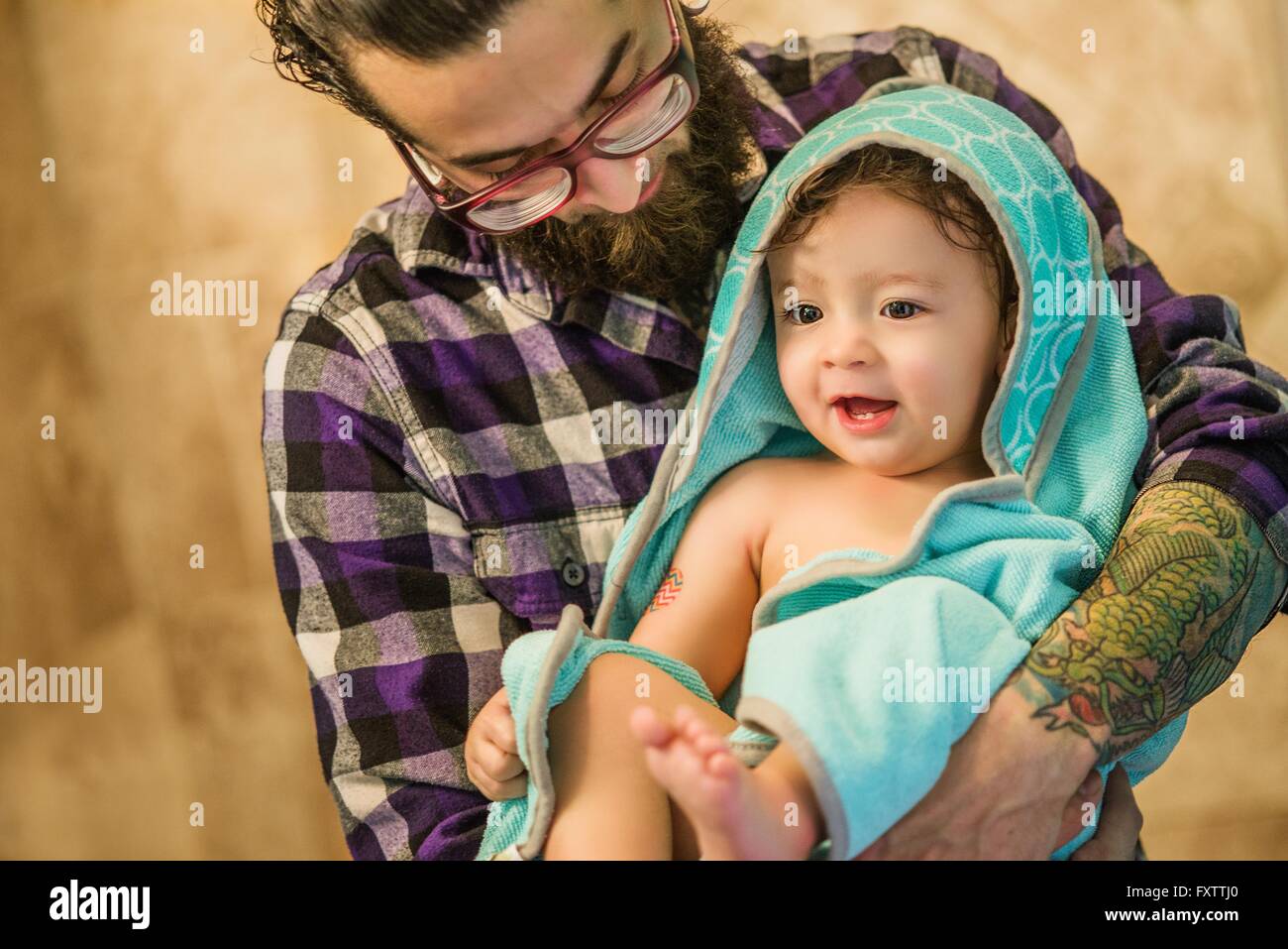 Giovane uomo bambino portando figlio avvolto in asciugamano Foto Stock
