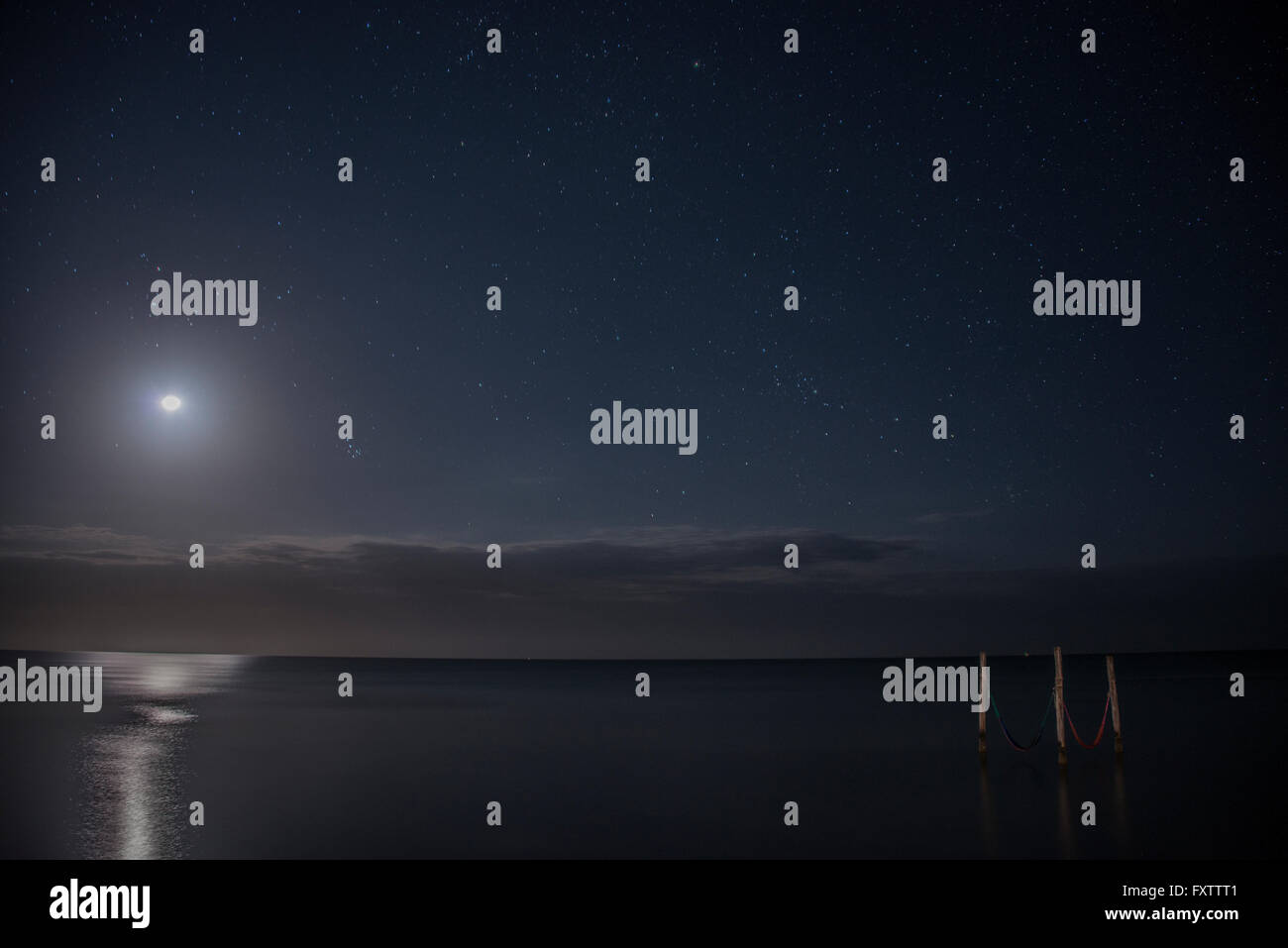 Cielo stellato e luna piena illumina iconico amache sulle acque, Isla Holbox, Messico Foto Stock