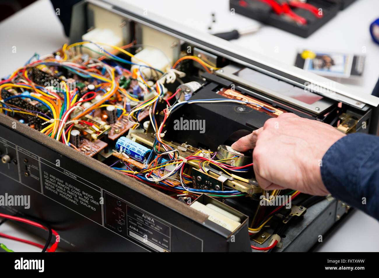 Hackney, Londra, Regno Unito. Riavviare partito volontario James Diamond esaminando una rotta Aiwa deck a cassetta. Foto Stock