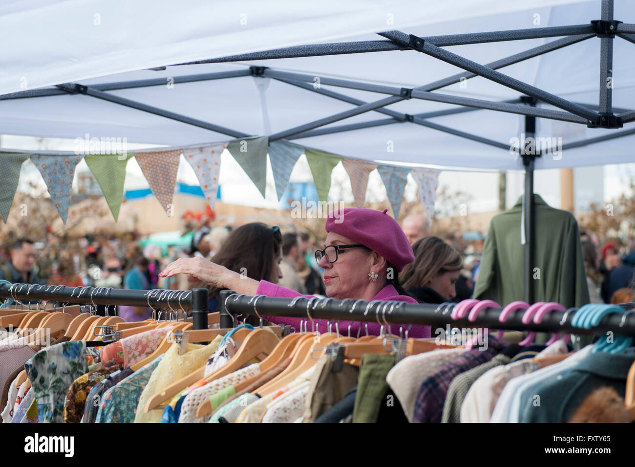 Una signora in beret tende al suo stallo di abbigliamento vintage a Classic car boot in vendita in Cubitt Square, Kings Cross Londra Foto Stock
