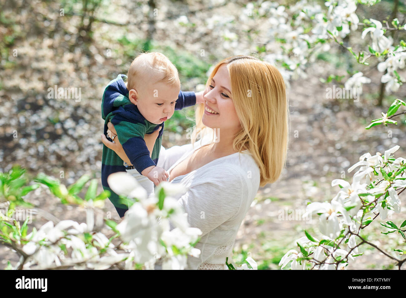 Little baby boy con la sua giovane madre nella fioritura Spring Garden Foto Stock