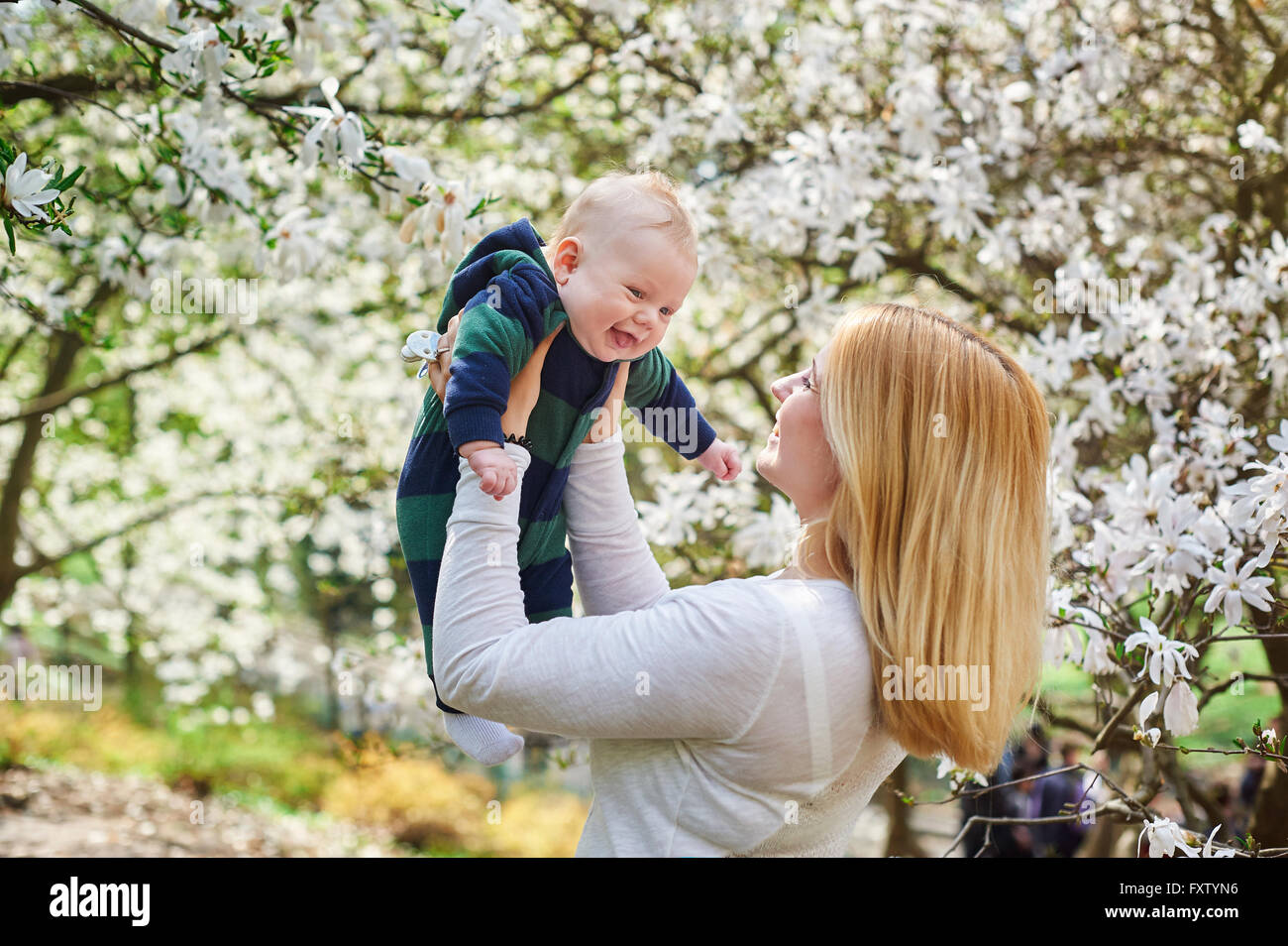 Little baby boy con la sua giovane madre nella fioritura Spring Garden Foto Stock