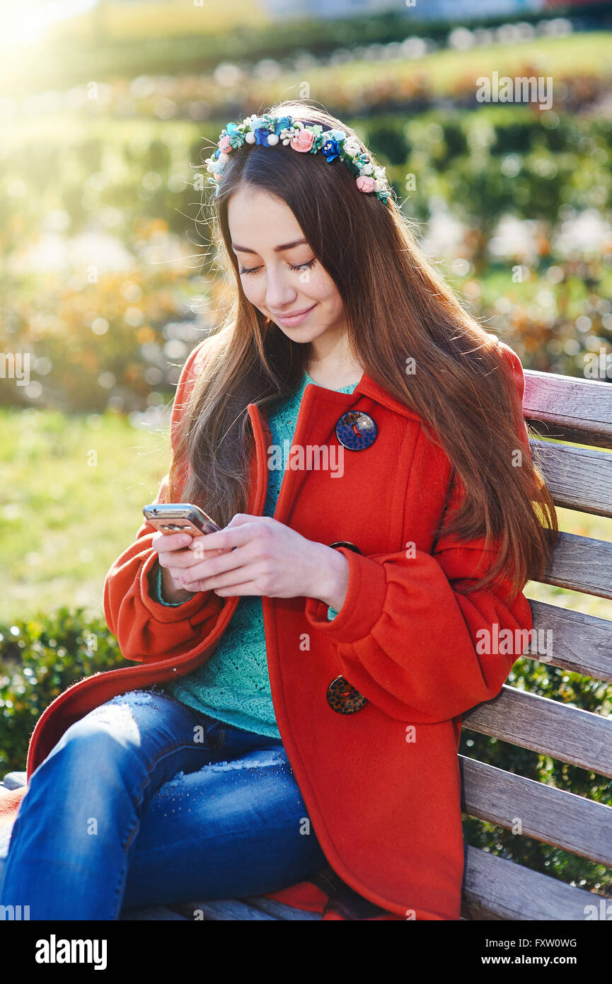 Bella donna Cappotto seduta sul banco in città Foto Stock