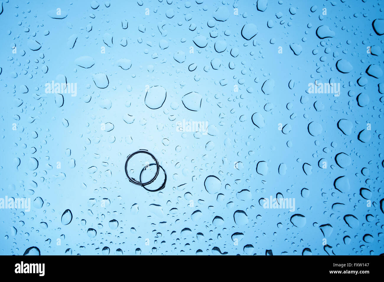 Sfondo di gocce di acqua e due anelli sul vetro Foto Stock