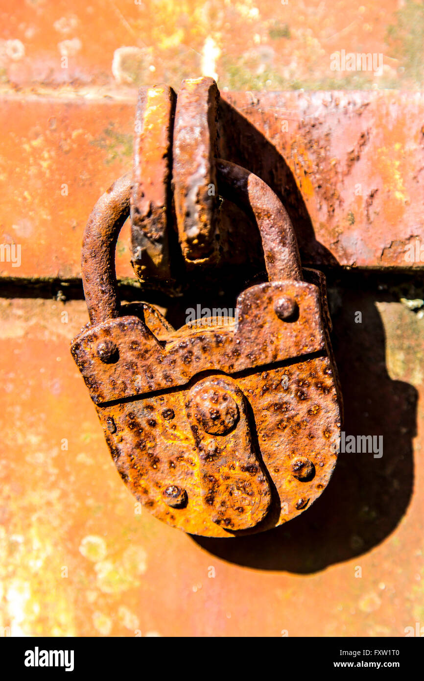 Vecchie e arrugginite, utilizzato lucchetto in una porta di metallo, chiuso, simbolo immagine, Foto Stock