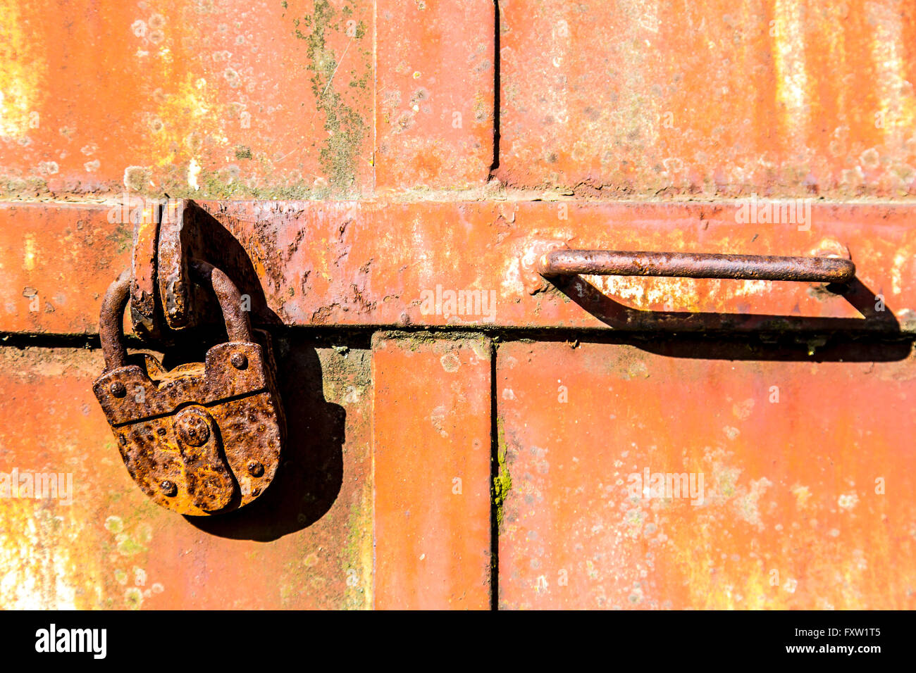 Vecchie e arrugginite, utilizzato lucchetto in una porta di metallo, chiuso, simbolo immagine, Foto Stock