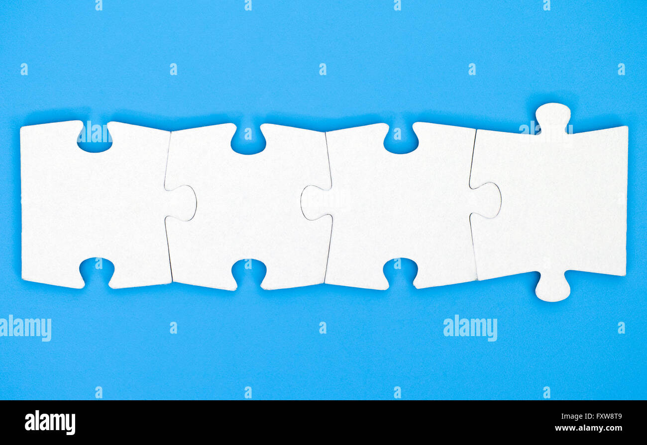 Quattro pezzi di un puzzle sono collegati insieme su sfondo blu Foto Stock