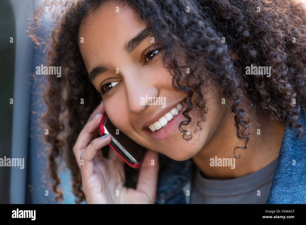 Bella felice razza mista americano africano ragazza adolescente femmine giovane donna sorridente con denti perfetti parlando al cellulare Foto Stock