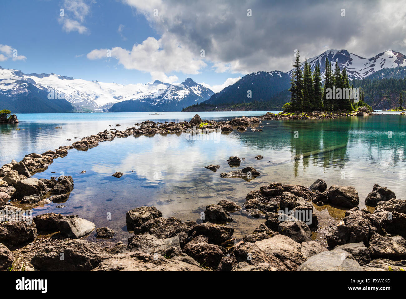 Tranquilla e chiare acque del lago Garibaldi riflettono gli alberi e le montagne in sfumature di blu e verde smeraldo e la bottiglia e verde Foto Stock