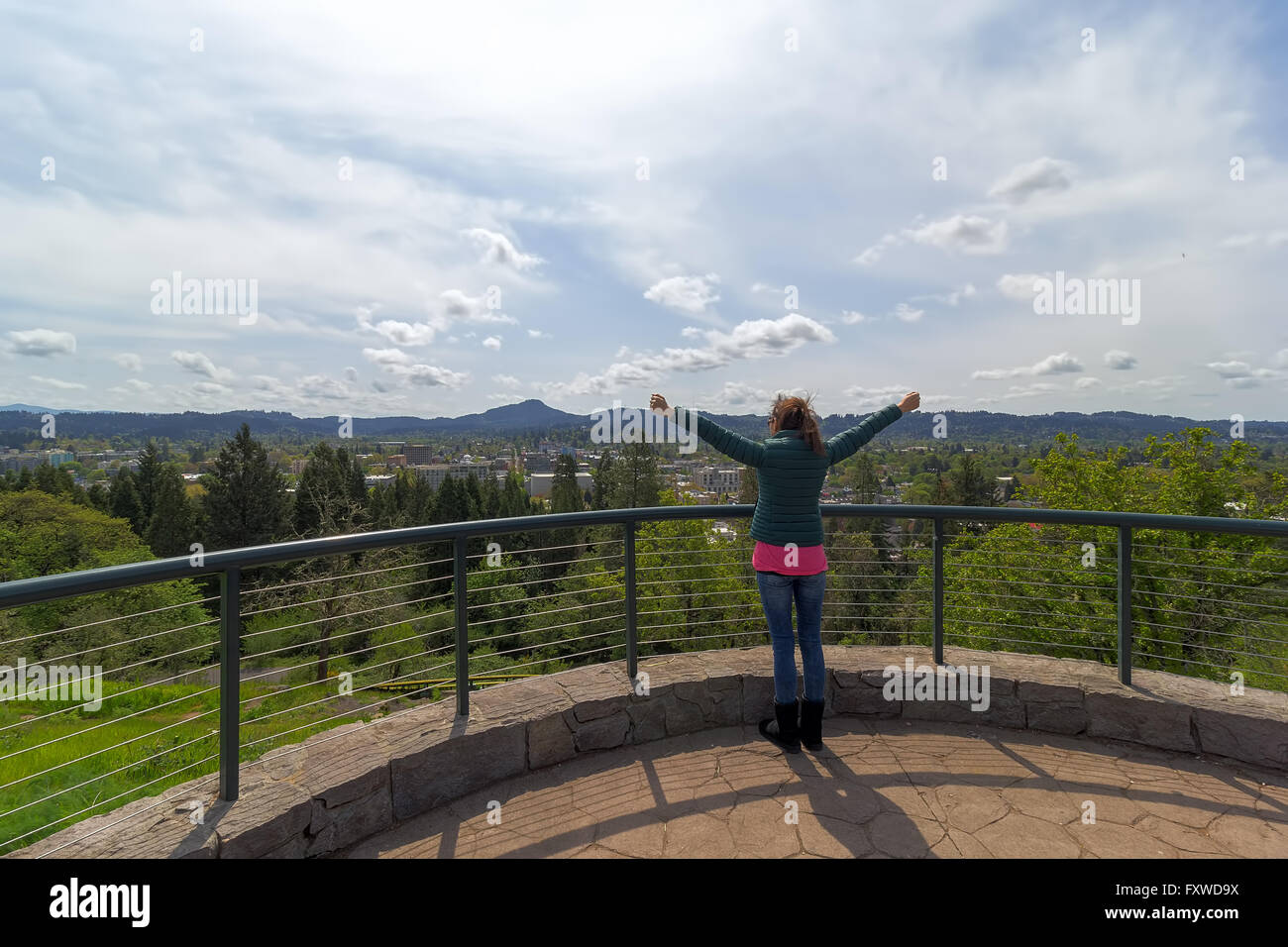 Donna braccio disteso sulla sommità della spellatrice Butte di punto di vista parco affacciato sul centro di Eugene, Oregon su una bella giornata Foto Stock