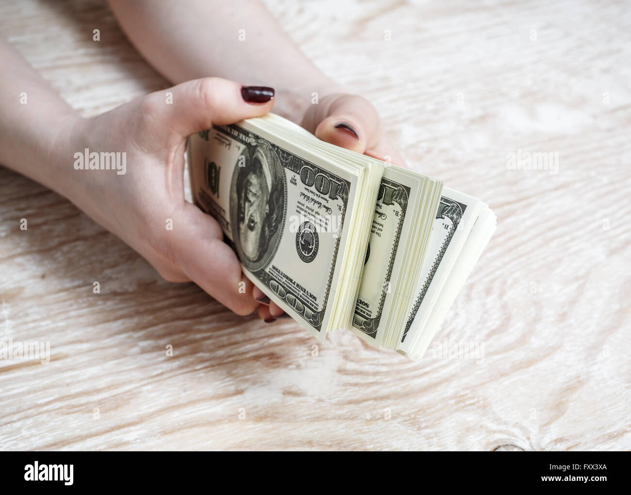 Una pila di soldi in mani femminili sulla luce sullo sfondo di legno. Di dollari nelle mani di. Denaro falso. Foto Stock