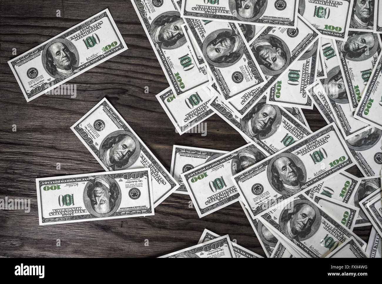 Molte banconote da cento dollari sul legno scuro dello sfondo. Denaro falso. Concetto di business tema. Foto Stock