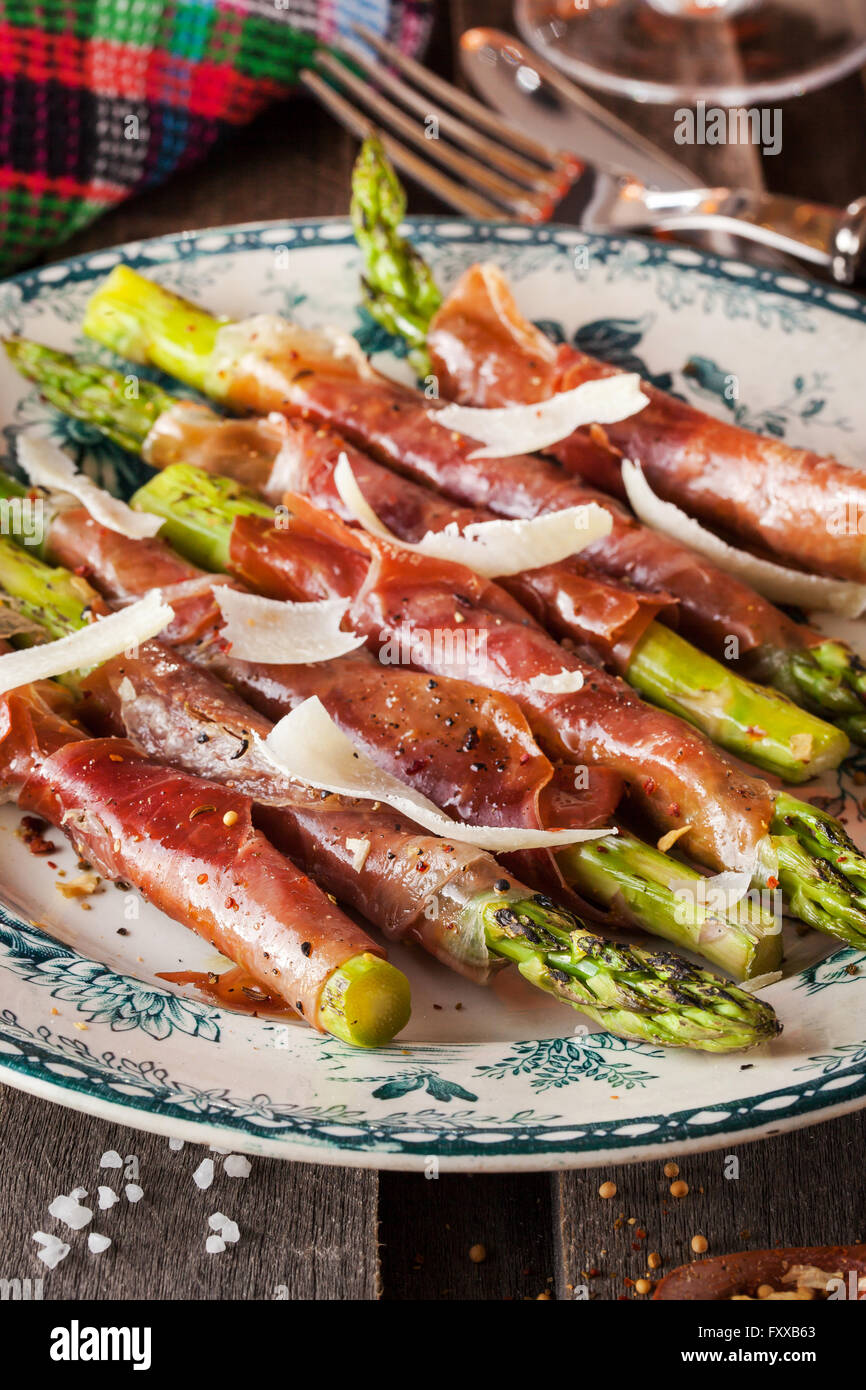 Freschi asparagi verdi avvolti nel prosciutto di Parma su piastra Foto Stock