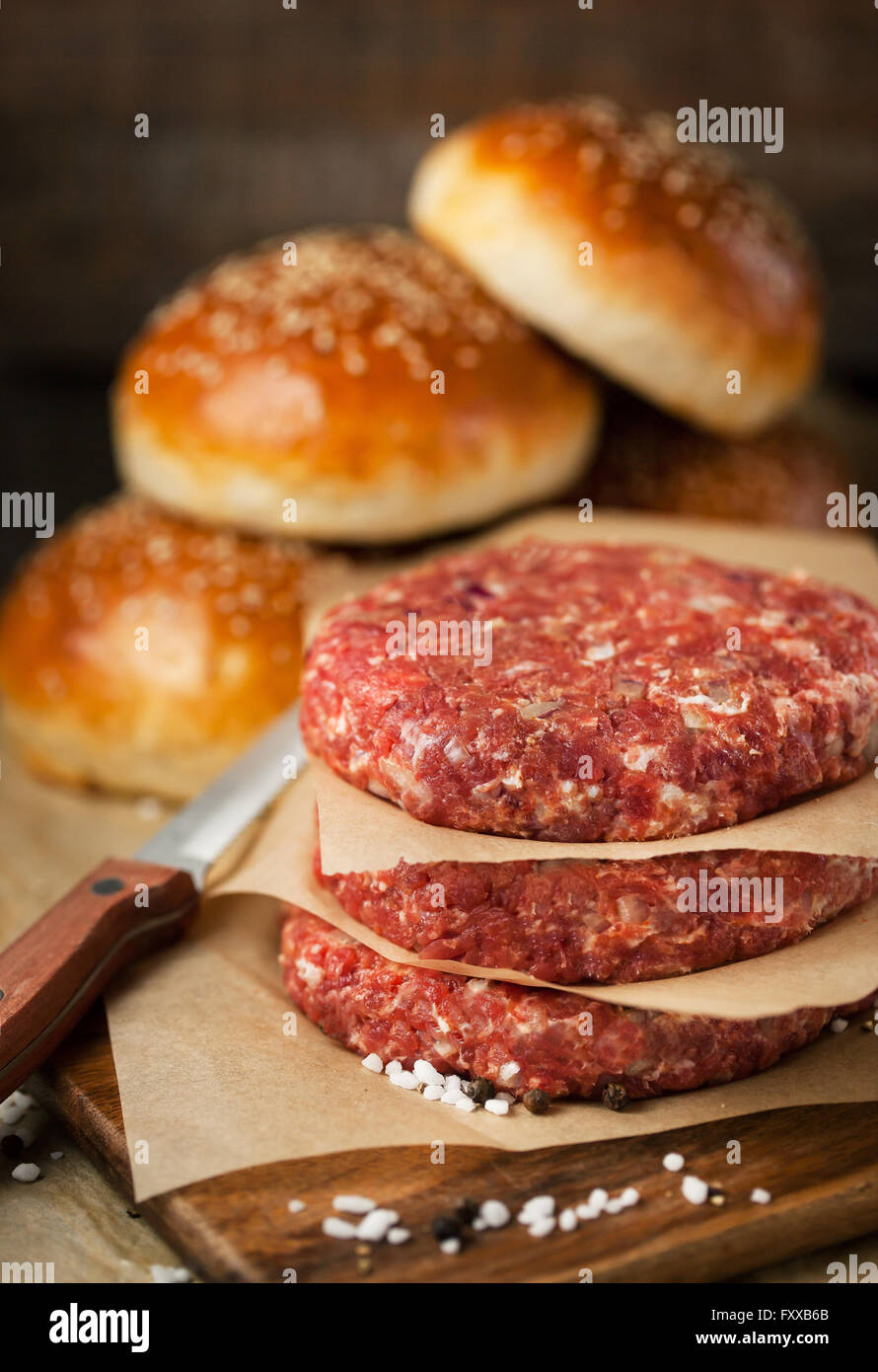 Materie di macinato di manzo bistecca di carne bistecche e hamburger panini su sfondo di legno, pronti per la cottura Foto Stock