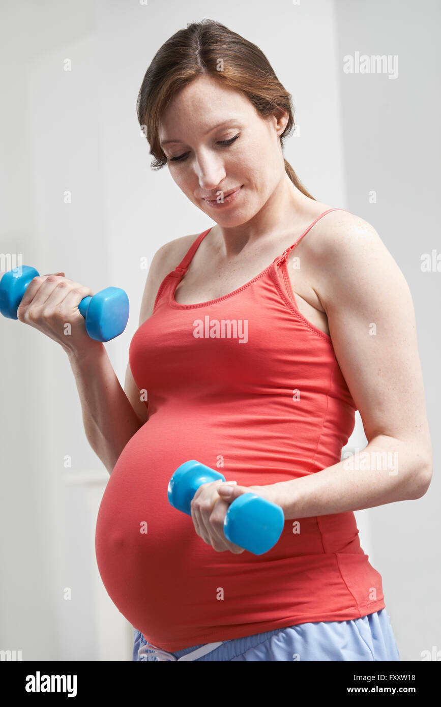 Donna incinta esercizio con pesi Foto Stock