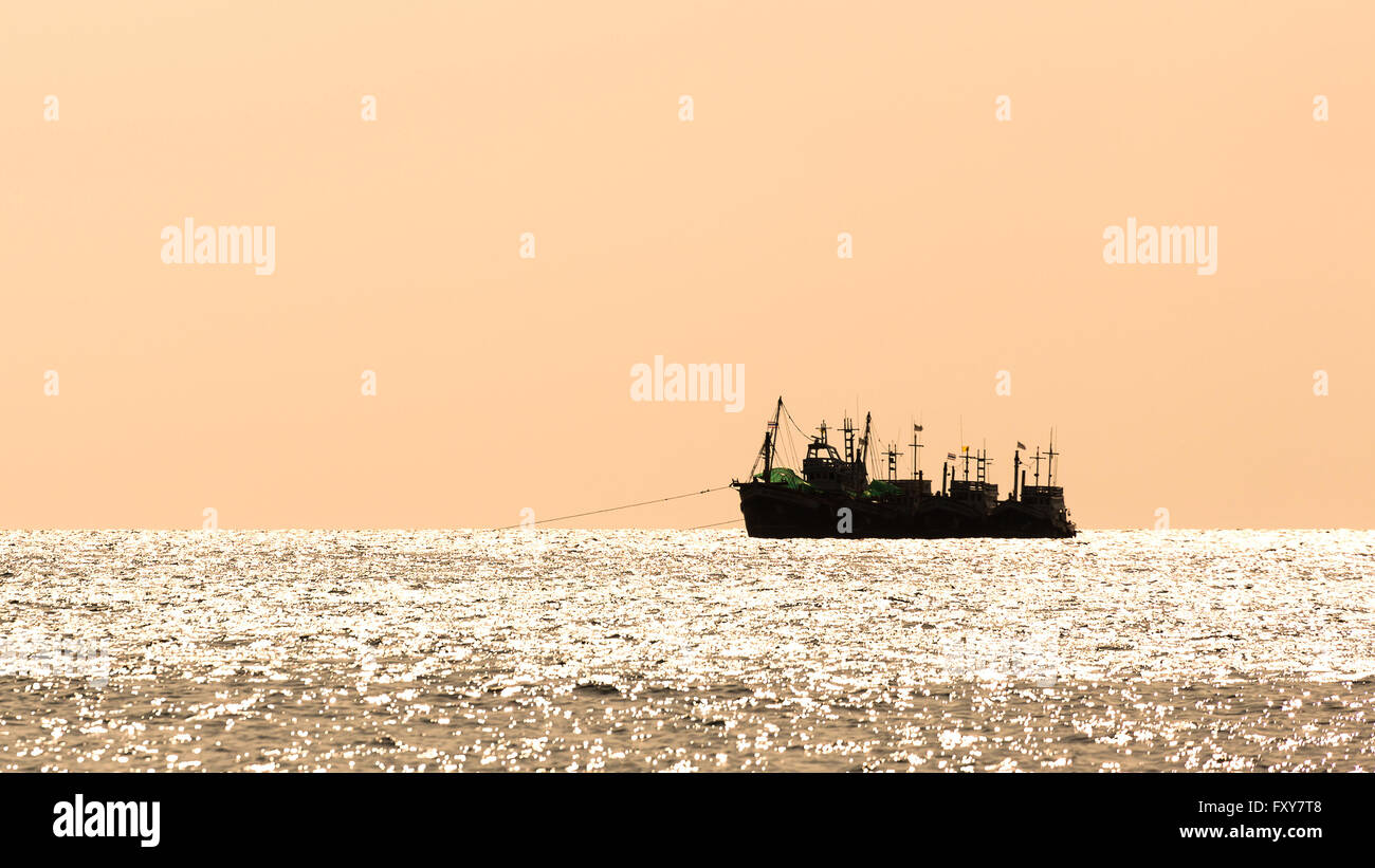 Stagliano gruppo di imbarcazioni di pesca che galleggiante su sventolando acqua con sullo sfondo di un Cielo di tramonto Foto Stock