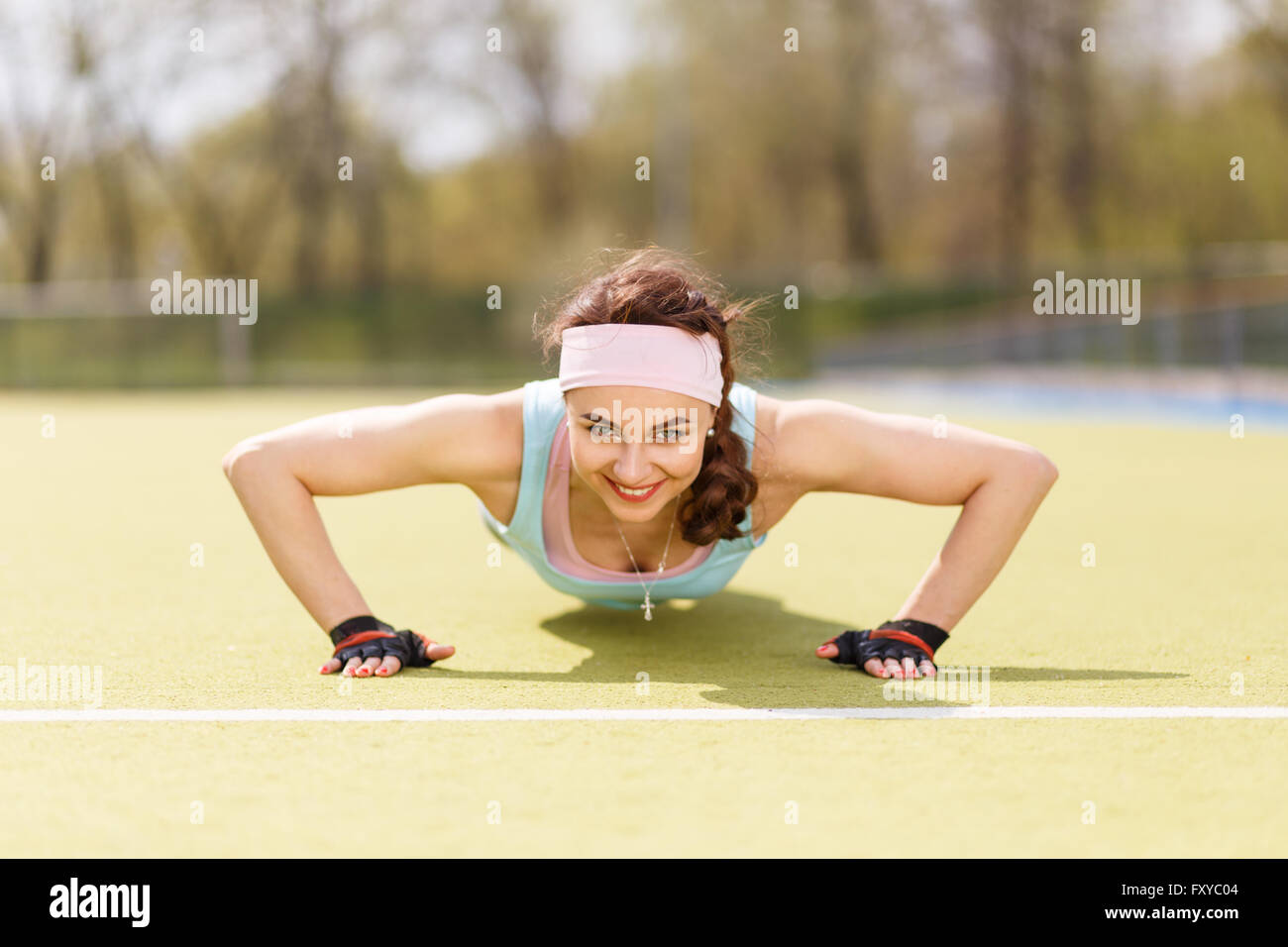 Giovane donna attraente facendo push-up o core esercizio sul campo in erba Foto Stock