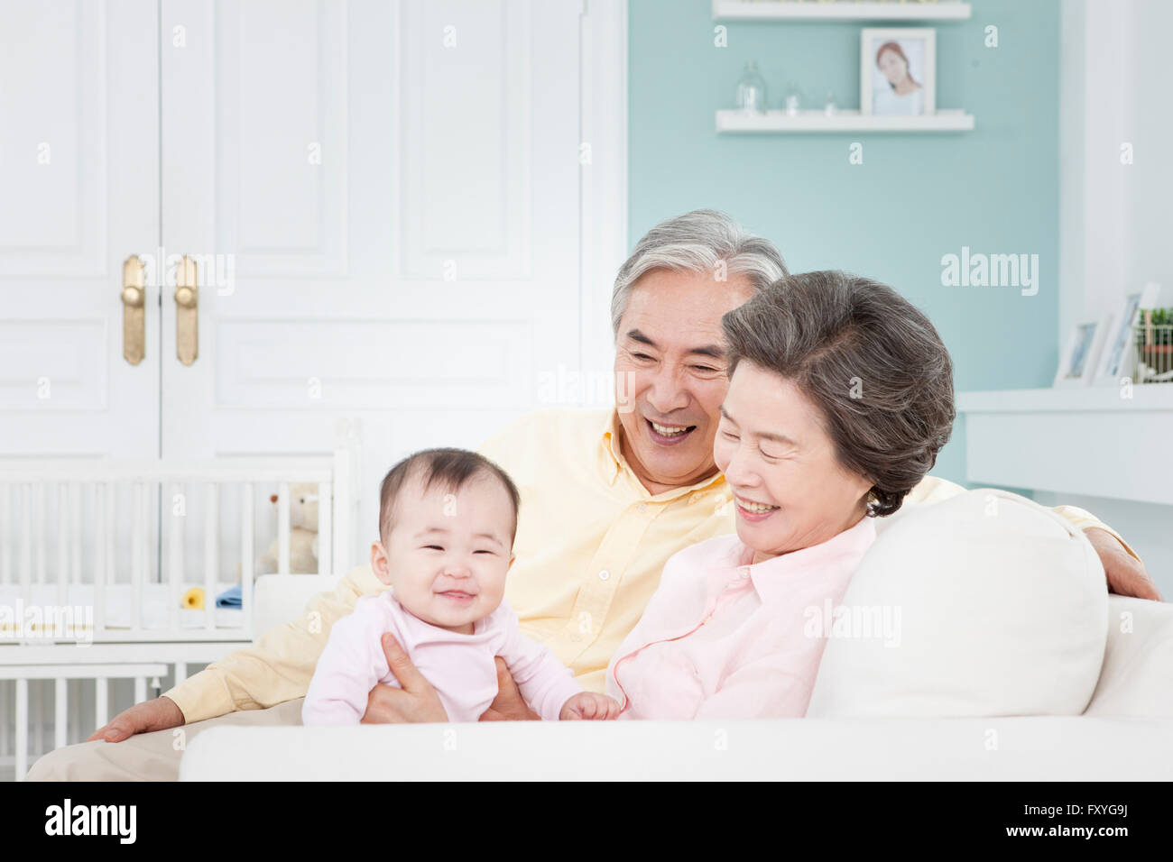 I nonni di prendersi cura di un bambino su un lettino tutti sorridenti Foto Stock