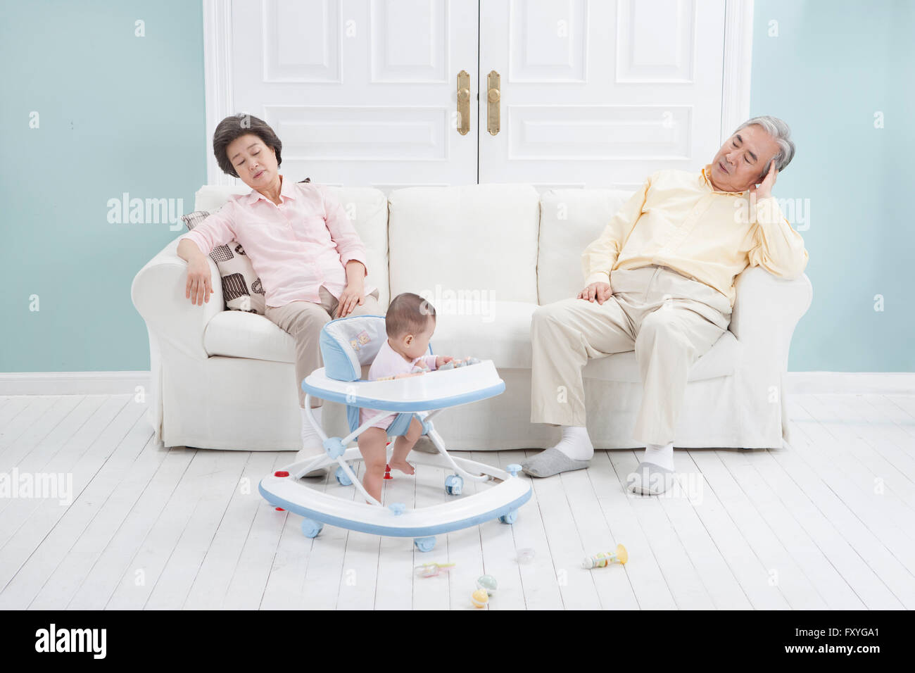 Nonni seduto su un divano stanco di prendersi cura di un bambino Foto Stock